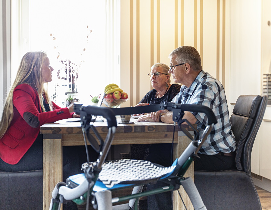 Drie mensen zitten aan tafel